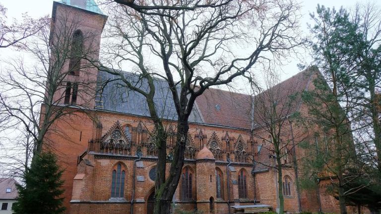 Red brick church among the trees on a foggy day. St. Co-Cathedral John the Baptist in Kamien Pomorski, Poland shutterstock_1666366828.jpg