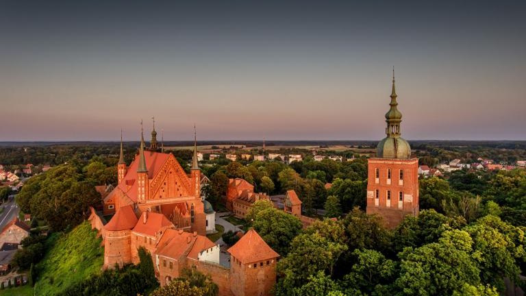 Great view of the beautiful city of Frombork located in Warmia, Poland. Cathedral Hill among trees at sunset shutterstock_2209862569.jpg